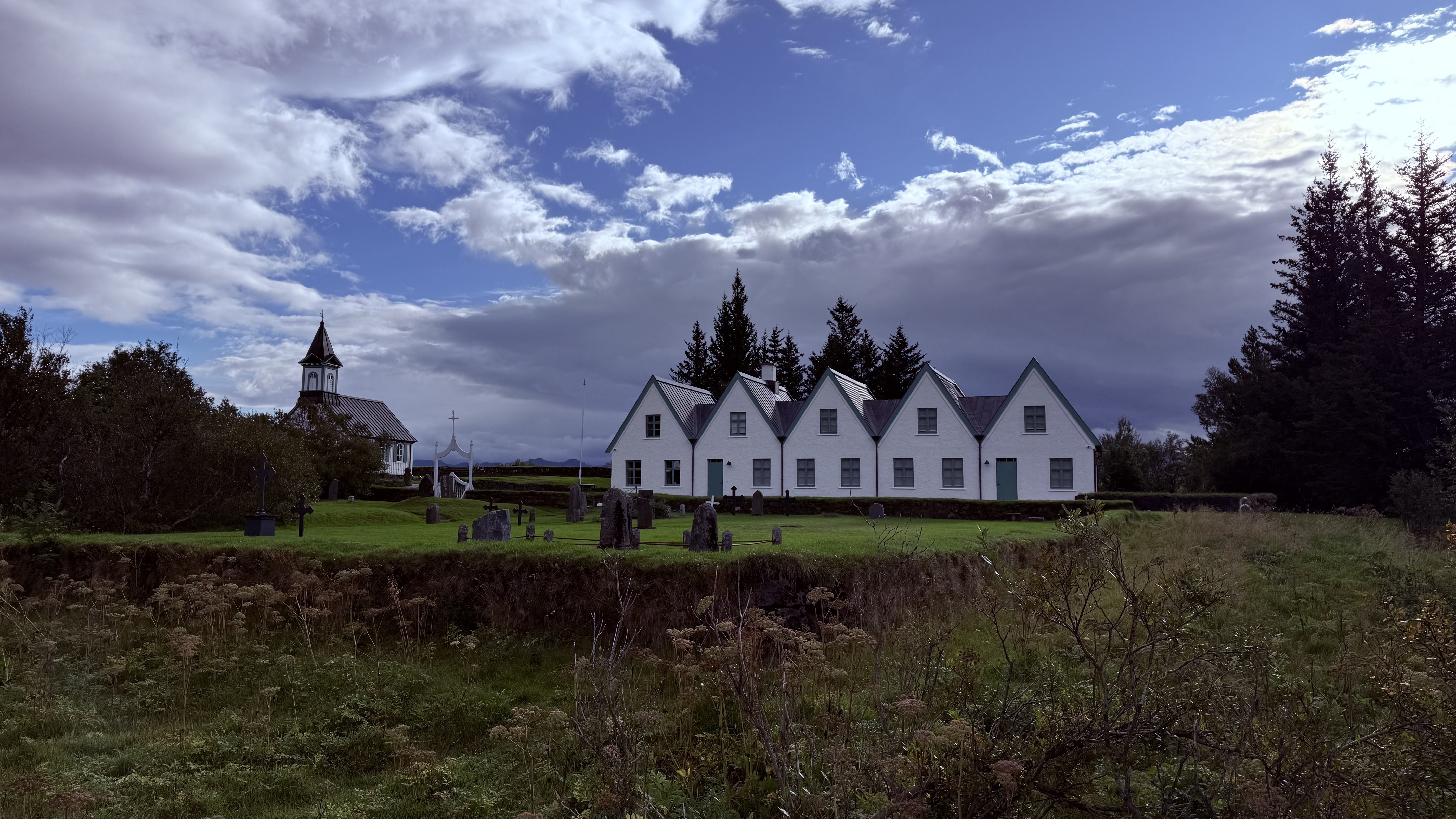 Historic white buildings and church at Thingvellir with graveyard