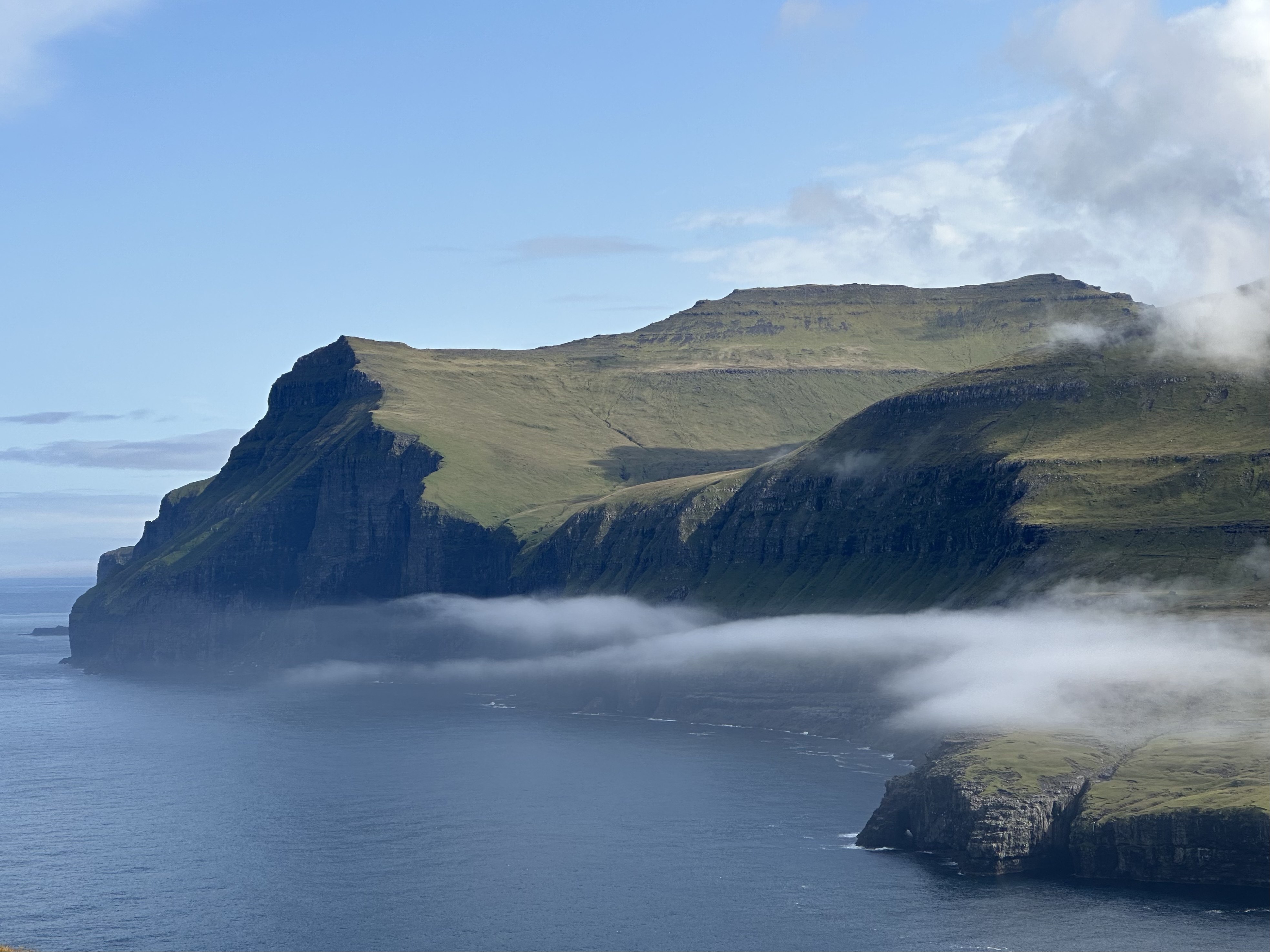 Dramatic Icelandic sea cliffs with low clouds rolling over the water