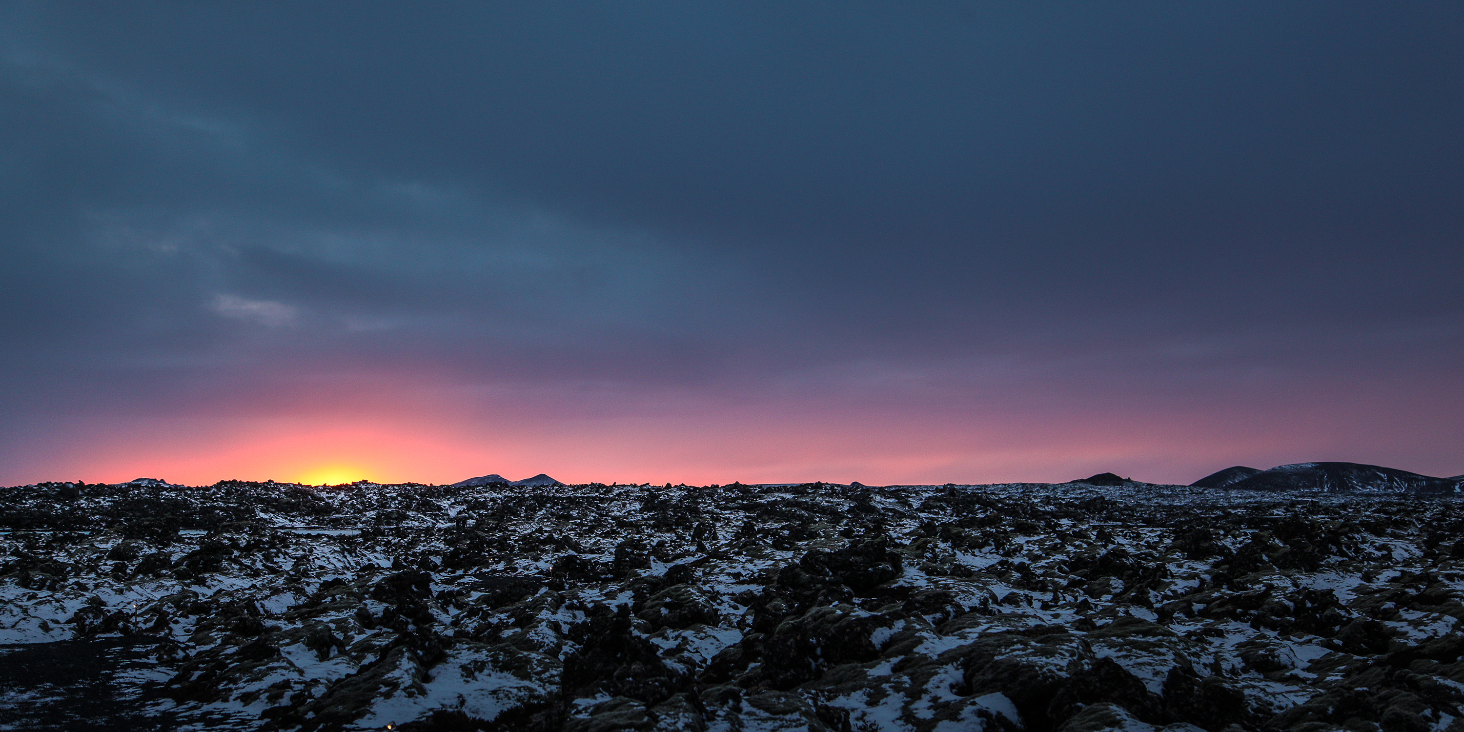 Sunset over Icelandic lava fields with golden light and distant mountains
